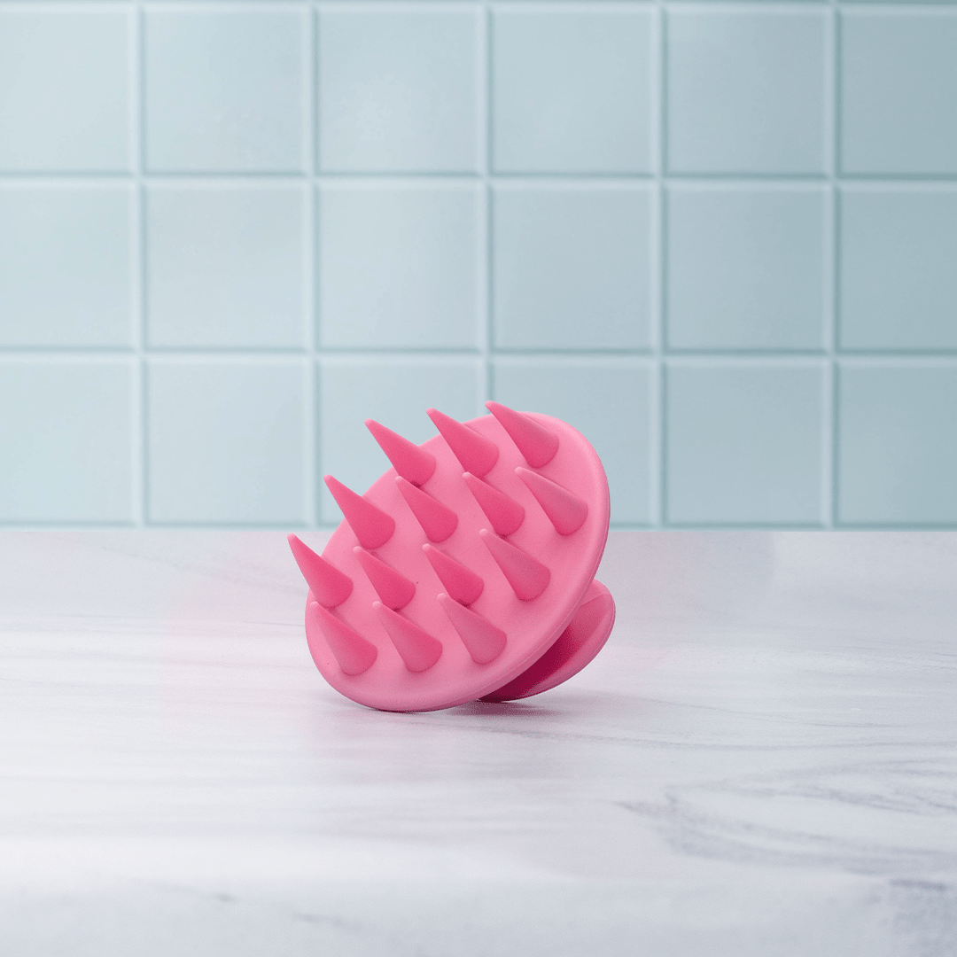 Pink silicone massager on a light blue tiled background